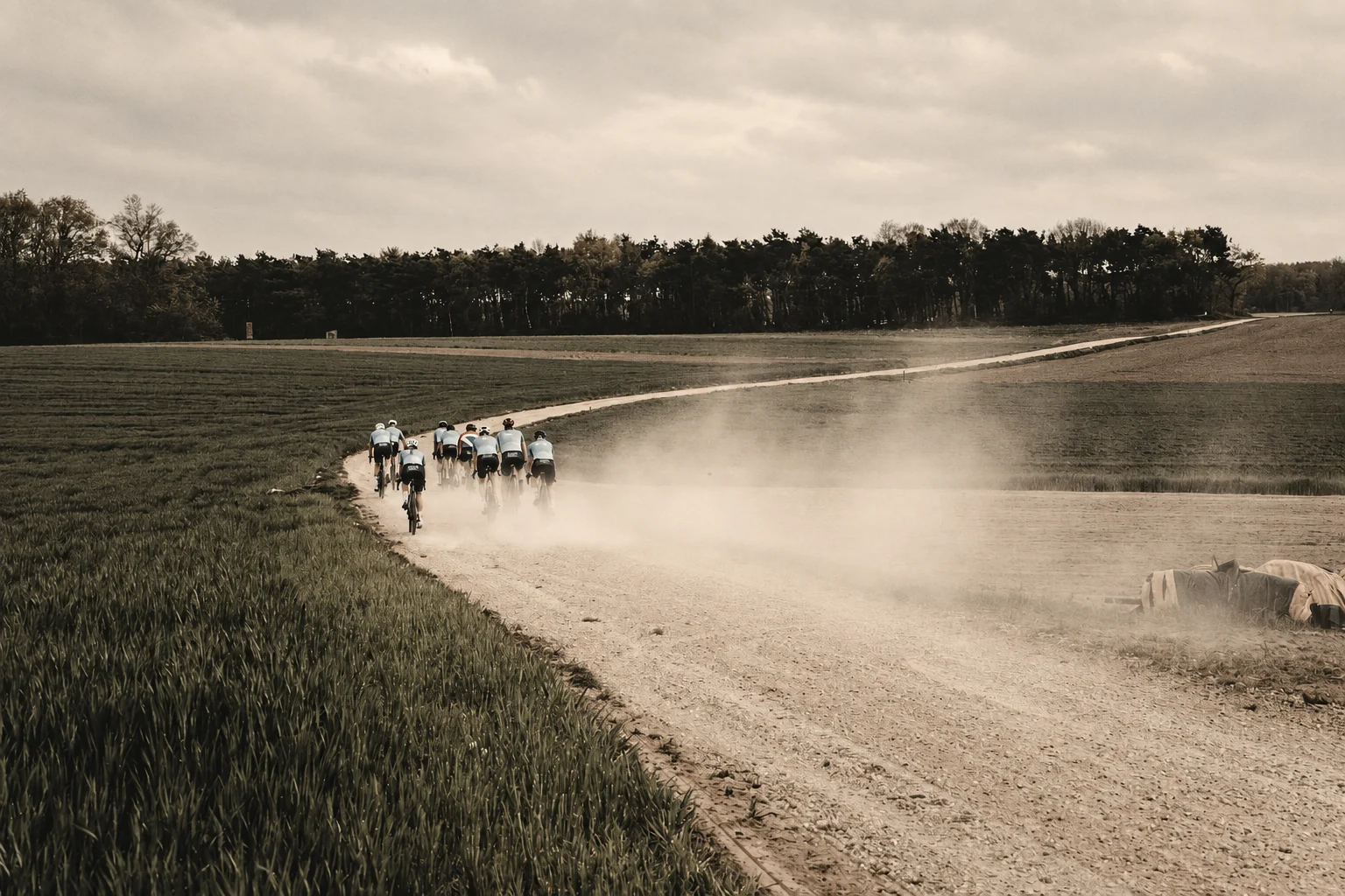 Groep wielrenners rijdt over een stoffige gravelweg door het Limburgse landschap